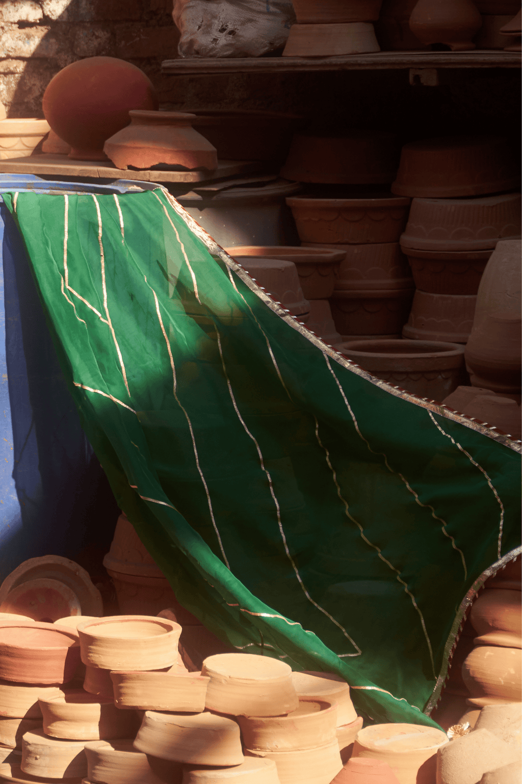 Stacks of ceramic pots with a green dupatta in the foreground