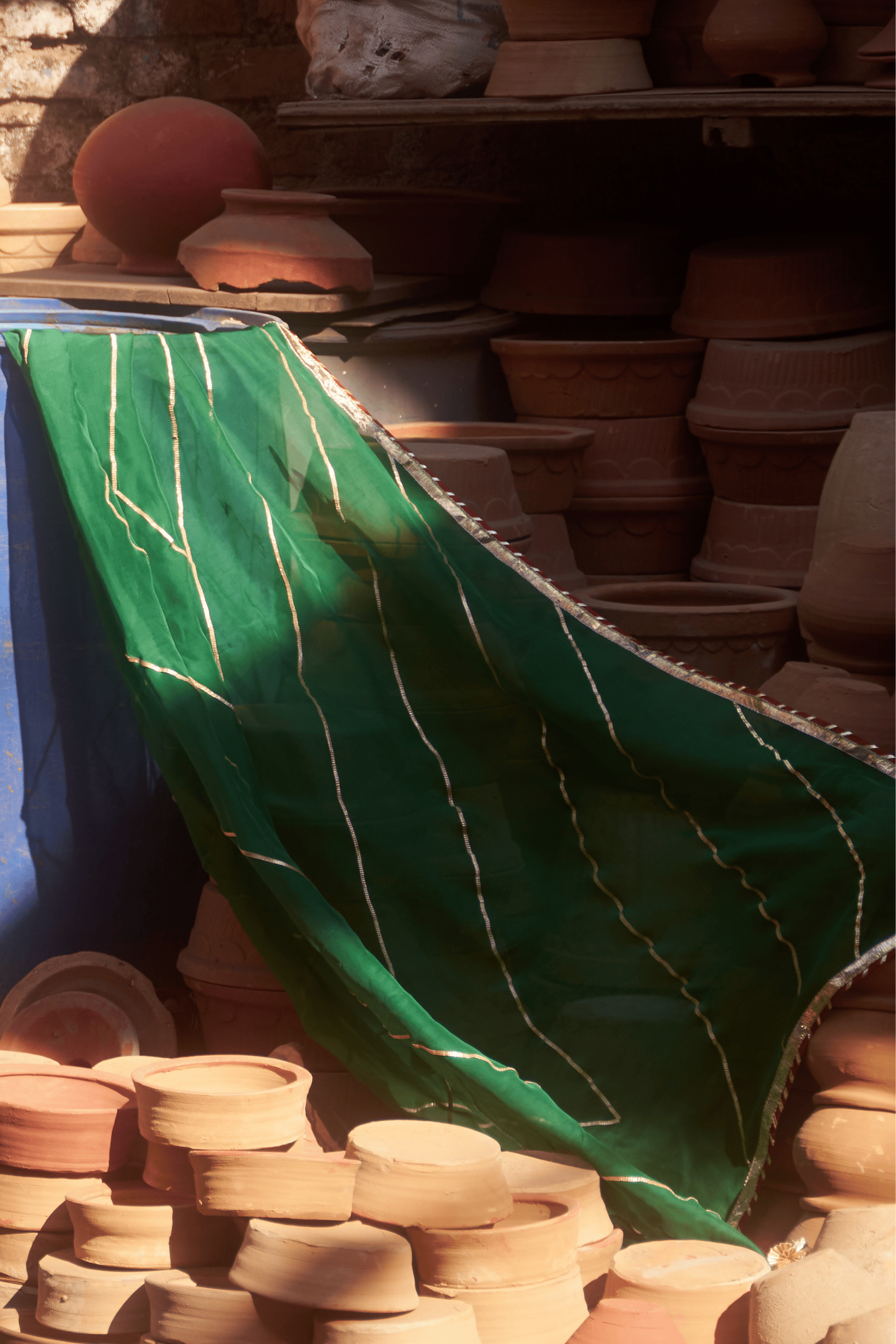Stacks of ceramic pots with a green dupatta in the foreground